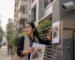 A worried pet owner searching for a missing cat near an apartment building in Bangladesh with a CCTV camera visible